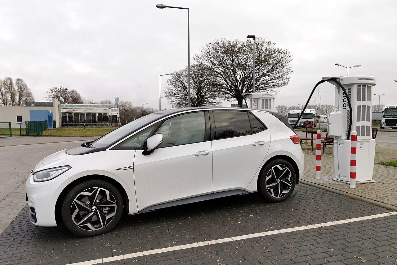 Electric hatchback connected to a tall rapid charging unit at a motorway rest area