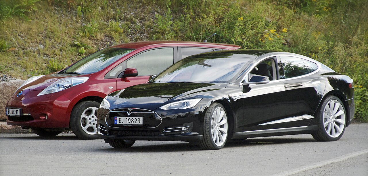 Two electric cars, a hatchback and a saloon, parked side by side outdoors in Norway