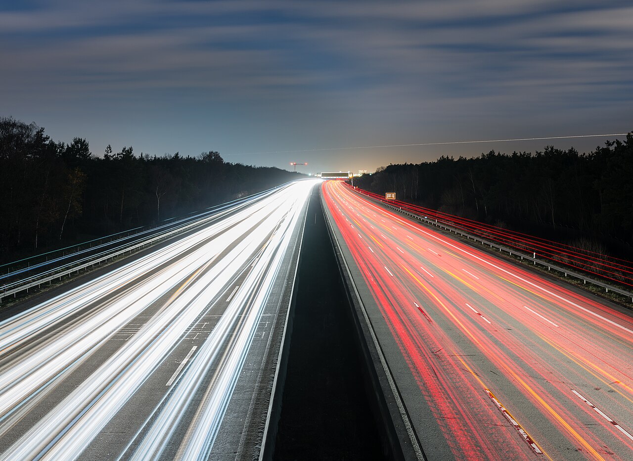 Wide multi-lane motorway running towards an airport visible on the horizon